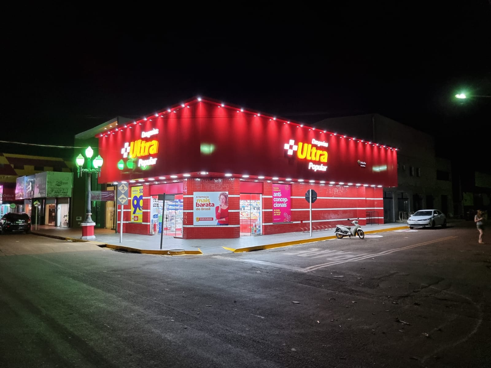 Fachada iluminada da Drogaria Ultrapopular a noite